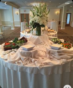 the table is covered with white linens and flowers