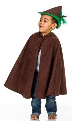 a young boy wearing a brown cape and green hat