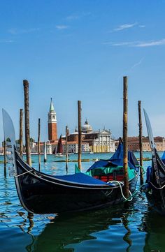 two gondolas are tied to poles in the water