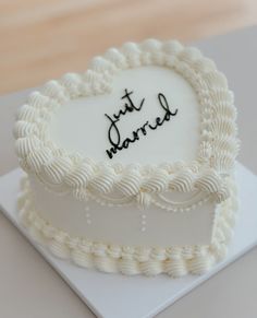 a heart shaped cake with the words just married written in black on it's frosting