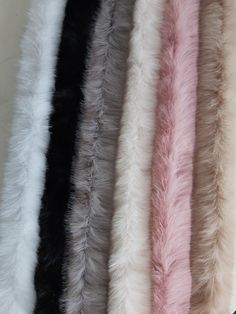 several colors of faux fur lined up on a white tablecloth with black, pink, and grey stripes