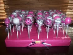 pink and white cake pops with zebra print on them are arranged in a box for display