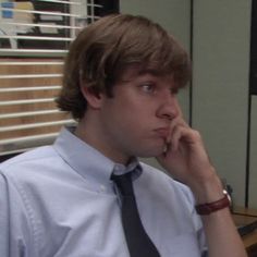 the young man is talking on his cell phone while sitting in an office cubicle