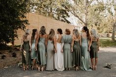 a group of women standing next to each other in front of a wall and trees