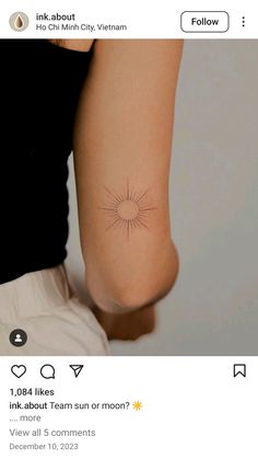 the back of a woman's arm with a small sun tattoo on her left side