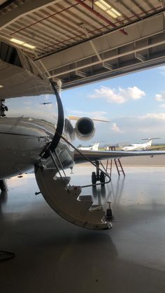 an airplane is parked in the hangar with its door open