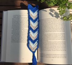 an open book with a crocheted tassel on top of it next to a plant