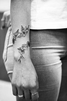 black and white photo of a woman's arm with flowers tattooed on the wrist