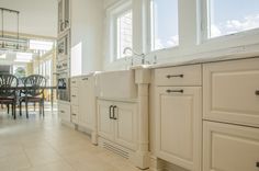 a large kitchen with white cabinets and marble counter tops, along with a dining room table in the background