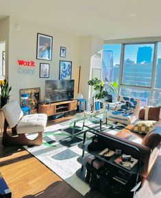 a living room filled with furniture and lots of windows overlooking the cityscape in the distance