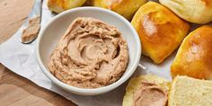 bread rolls with peanut butter in a white bowl on a wooden table next to it