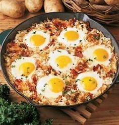 two fried eggs are in a skillet on a wooden table with other food items