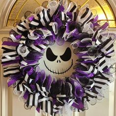 a wreath decorated with black and white stripes and a skull on the front door for halloween