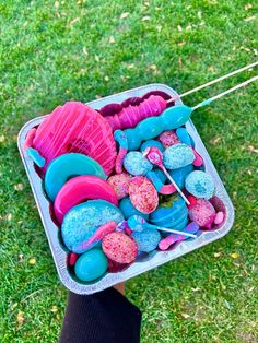 a person holding a container filled with toys on top of green grass in the park