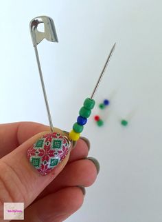 a person is holding some pins with beads on them