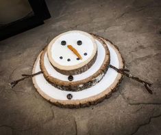 a snowman made out of wood sitting on top of a stone floor next to another piece of wood