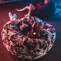 two people sitting on bean bag chairs in a room with red carpet and blue lighting