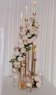 a tall vase filled with lots of flowers next to candles and glass vases on top of a table