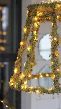 a light up letter hanging from the side of a door with moss and lights on it