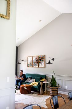 a man sitting on top of a green couch in a living room next to a wooden table