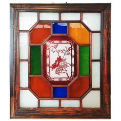 a stained glass window with flowers and leaves on it's center piece, hanging from the wall