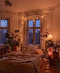 a bed room with a neatly made bed and lots of plants on the windowsill