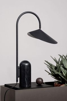 a black lamp sitting on top of a table next to a potted plant