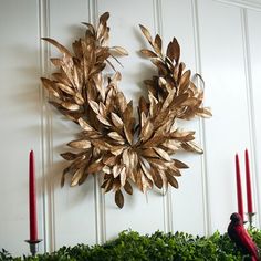 a metal wreath is hanging on the wall next to candles and greenery with red birds