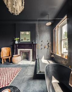 a bathroom with black walls and an old fashioned bathtub next to a fire place