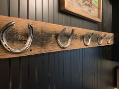 three horseshoes are mounted on a wooden coat rack in the corner of a room