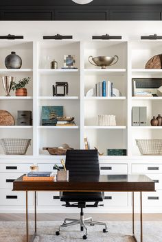 a home office with white bookcases and black chair