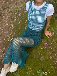 a woman sitting on top of a green grass covered field