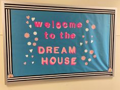 a sign that says welcome to the dream house with flowers and hearts in pink on blue