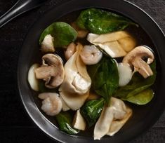 a black bowl filled with mushrooms and spinach