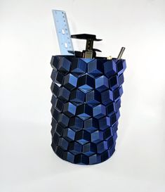 a pen holder made out of blue cubes with a ruler on the top and a tool in it