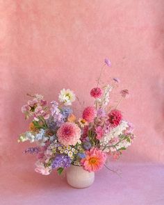 a vase filled with lots of different colored flowers on top of a pink tablecloth