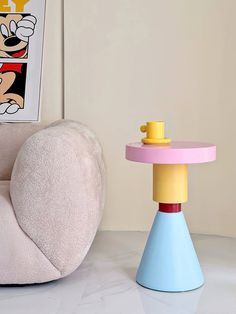 a chair and table with mickey mouse on it in a room next to a wall