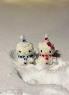 two hello kitty figurines sitting in the snow