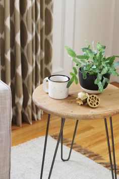 a small table with some plants on it and a mug sitting on top of it