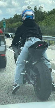 a man riding on the back of a motorcycle down a road next to a car