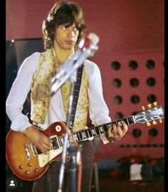 a young man playing an electric guitar on stage