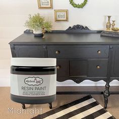 a black dresser with a jar of paint sitting on it's top next to a rug