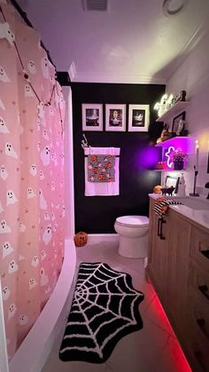 a bathroom decorated for halloween with ghost decorations on the shower curtain, rug and toilet