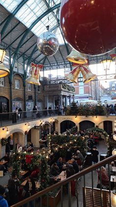 an indoor mall with christmas decorations and people sitting at tables in the center, surrounded by lights