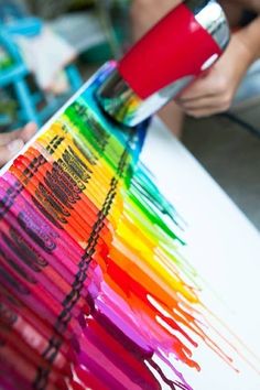 someone is using a paintbrush to create a rainbow - like painting on a piece of paper