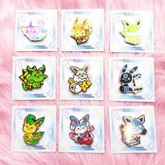 six different pokemon pin badges sitting on top of a pink fur covered surface with white squares