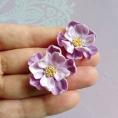 two small purple and white flowers are in someone's hand