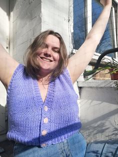 a woman sitting on the ground with her arms in the air and smiling at the camera