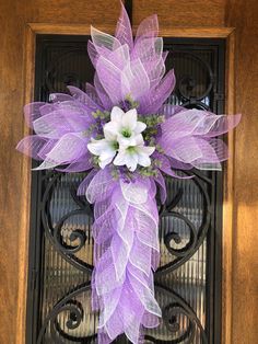 a purple and white wreath with flowers on the front door