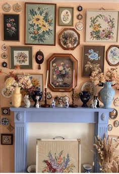 a blue mantle topped with pictures and vases filled with flowers next to a fire place